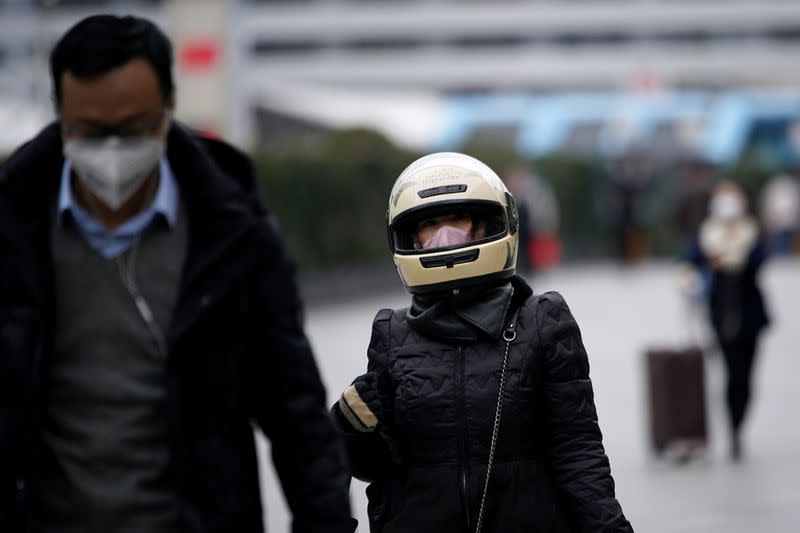 A woman wearing a helmet and a mask is seen upon her arrival at Shanghai railway station in Shanghai