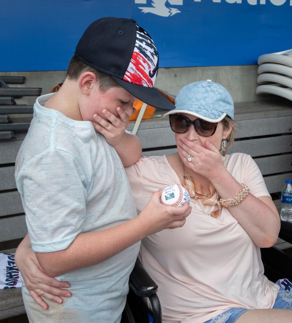 Amanda "Mandi" Furness, right, and her son, Hudson Furness, react to being presented with an autographed baseball in the dugout at Blue Wahoos Stadium in Pensacola on Monday. Mandi Furness, who has been battling lupus and multiple sclerosis, decided to use her My Wish granted by Covenant Care to see her 10-year-old son play baseball at the stadium.