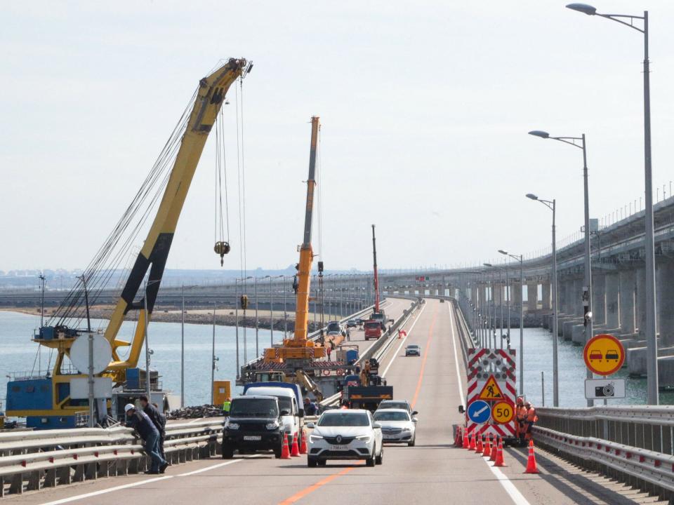 This picture taken on October 13, 2022 shows workers restoring damaged parts of the Kerch Bridge that links Crimea to Russia, which was hit by a blast on October 8, 2022.