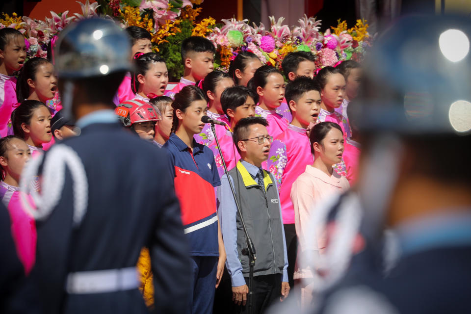 中華民國中樞暨各界慶祝110年國慶大會今天舉行，衛福部疾管署副署長羅一鈞（前中）、東奧銅牌得主羅嘉翎（前中左）等6人偕同國立客家兒童合唱團領唱國歌。（中央社）