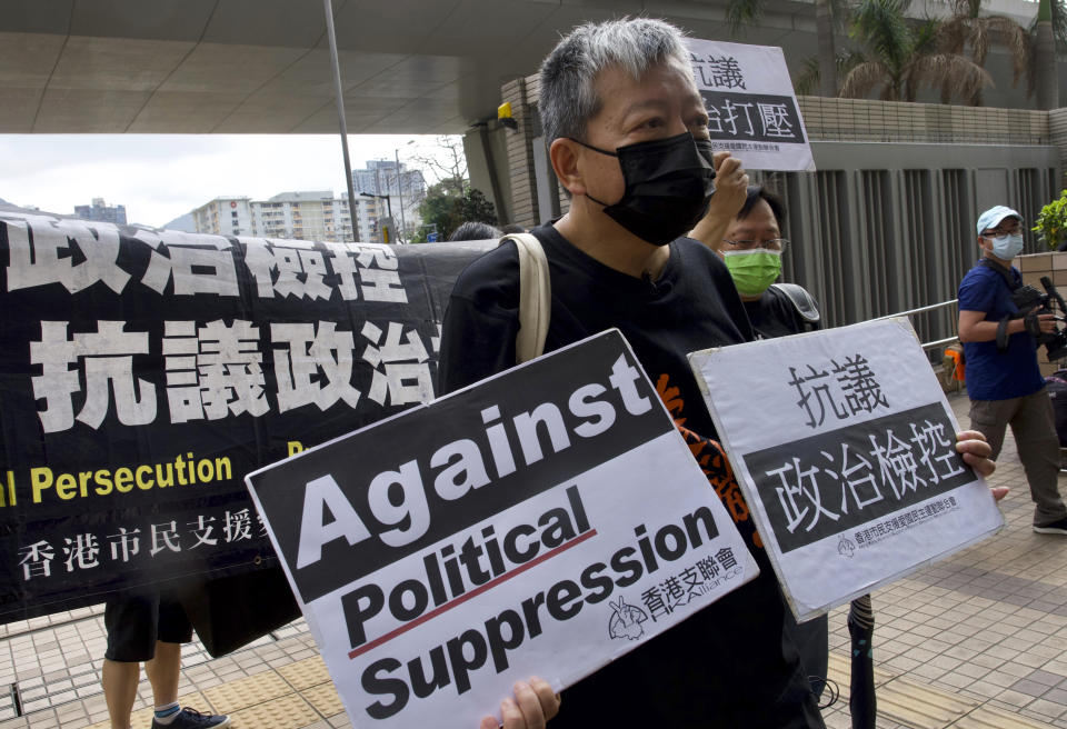 Pro-democracy activist Lee Cheuk-yan, center, holds placards as he arrives at a court in Hong Kong Thursday, April 1, 2021. Seven pro-democracy advocates, including media tycoon Jimmy Lai and veteran of the city's democracy movement Martin Lee, are expected to be handed a verdict for organizing and participating in an illegal assembly during massive anti-government protests in 2019 as Hong Kong continues its crackdown on dissent. (AP Photo/Vincent Yu)