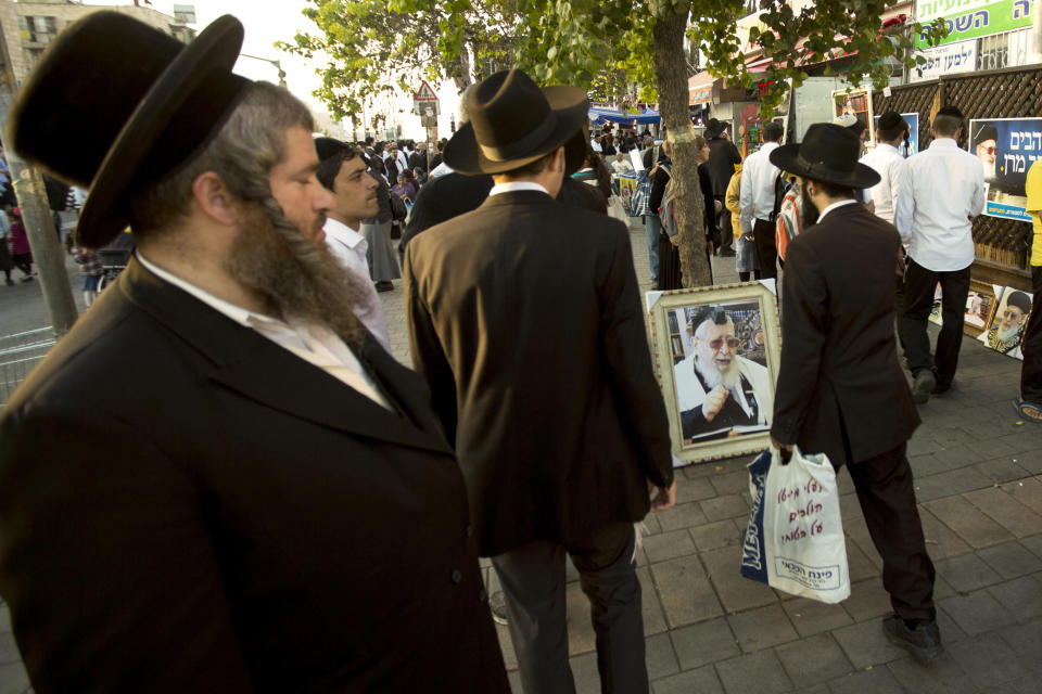 File - In this Oct. 13, 2013 file photo, ultra-Orthodox Jewish men walk past a picture of the late religious spiritual leader of Israel's Sephardic Jews, Rabbi Ovadia Yosef, at a ceremony a week after his funeral in Jerusalem. The Spanish conservative government, which enjoys an absolute majority in Parliament, plans to make amends in weeks to come with a law that offers citizenship to the legions of Jews forced to flee Spain in 1492. (AP Photo/Sebastian Scheiner, File)