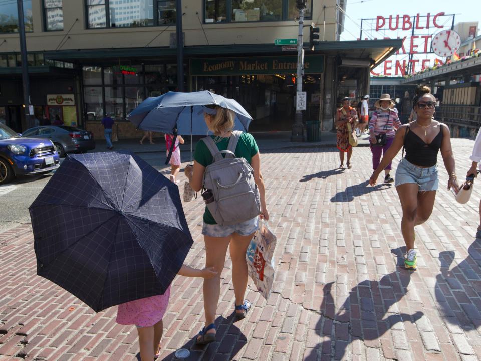 A woman and her daughter carry umbrellas while walking through Seattle's Public Market.
