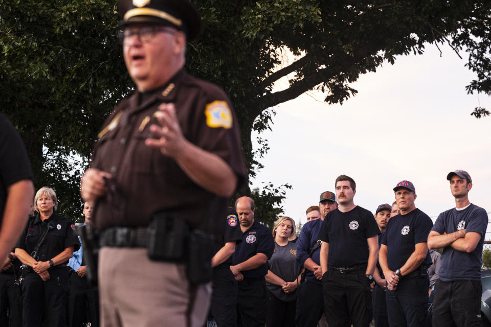 Emergency responders listen as Kalamazoo County Sheriff Richard Fuller talks briefly about Deputy Ryan Proxmire during a vigil outside the Sheriff office in Kalamazoo, Mich., Sunday, Aug. 15, 2021. A deputy in Michigan has died after being wounded during a chase with a gunman. The Kalamazoo County Sheriff’s Office says Deputy Ryan Proxmire died Sunday. Deputies encountered the suspect Saturday evening at a gas station in Galesburg and a chase ensued. (Joel Bissell/Kalamazoo Gazette via AP)