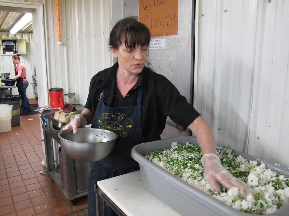 In this Wednesday, April 10, 2013 photo, Catering Manager, Tracy Wilson, at the Country Store market, mixes rice into a pork mixture to make boudin, in Pennsdale, Pa. The sausage is popular in Louisiana. An influx of workers from the South to fill jobs in the natural gas industry in north-central Pennsylvania has led area catering businesses, restaurants and grocery stores to offer more Southern cuisine like jambalaya and boudin. (AP Photo/Genaro C. Armas)