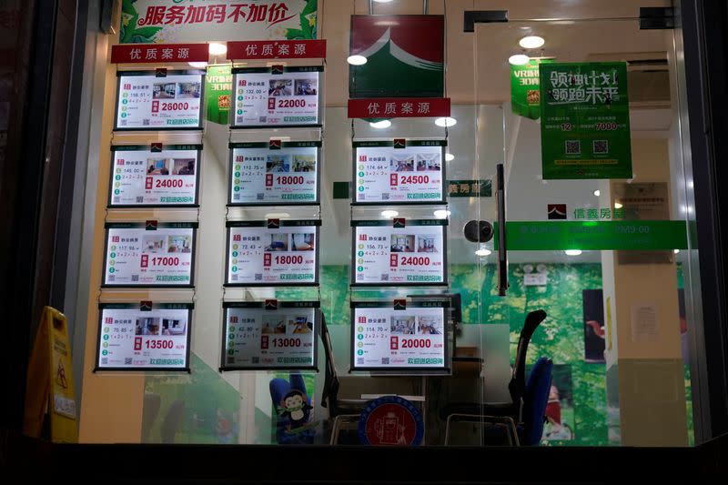 A real estate agency's window displays cards advertising apartments, along a street in Shanghai