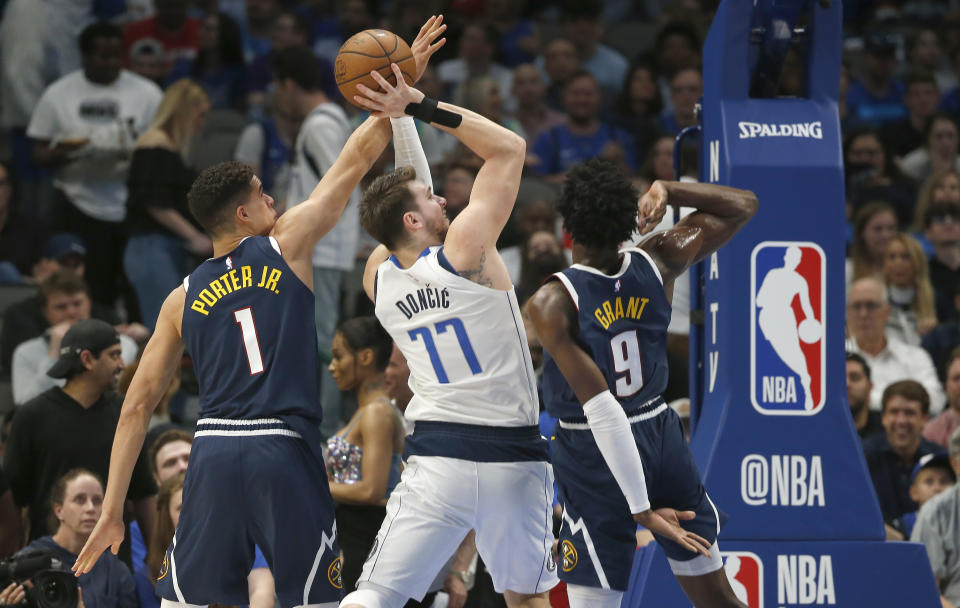 Dallas Mavericks guard Luka Doncic (77) shoots as Denver Nuggets forwards Michael Porter Jr. (1) and Jerami Grant (9) defend during the first half of an NBA basketball game Wednesday, March 11, 2020, in Dallas. (AP Photo/Ron Jenkins)