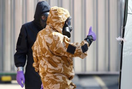 Forensic investigators, wearing protective suits, emerge from the rear of John Baker House, after it was confirmed that two people had been poisoned with the nerve-agent Novichok, in Amesbury, Britain, July 6, 2018. REUTERS/Henry Nicholls/Files