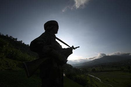 An Indian army soldier stands guard while patrolling near the Line of Control, a ceasefire line dividing Kashmir between India and Pakistan, in Poonch district August 7, 2013. REUTERS/Mukesh Gupta/Files