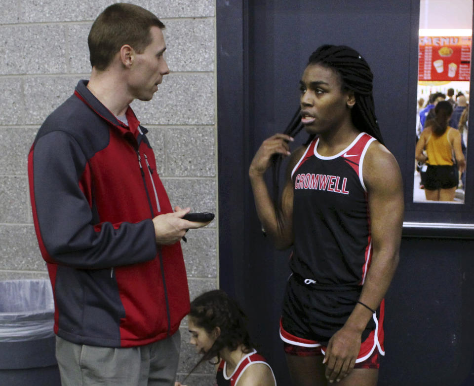 In this Thursday, Feb. 7, 2019 photo, Cromwell High School track coach Brian Calhoun, left, speaks to transgender athlete Andraya Yearwood during a break at a meet at Hillhouse High School in New Haven, Conn. Yearwood, a 17-year-old junior at Cromwell High School, is one of two transgender high school sprinters in Connecticut, transitioning to female. (AP Photo/Pat Eaton-Robb)