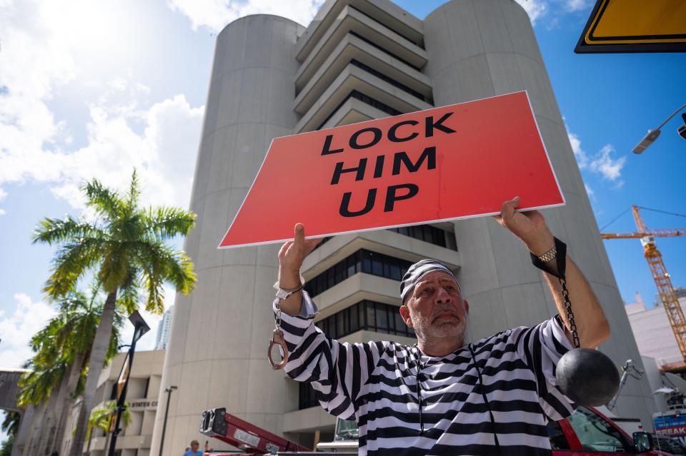 Domenic Santana, Miami, holds a sign reading "LOCK HIM UP," while wearing a striped prisoner's costume outside the Wilkie D. Ferguson Jr. U.S. Courthouse on Tuesday in Miami. Former President Donald Trump was arraigned Tuesday afternoon, facing charges that he illegally retained national security documents after leaving office.