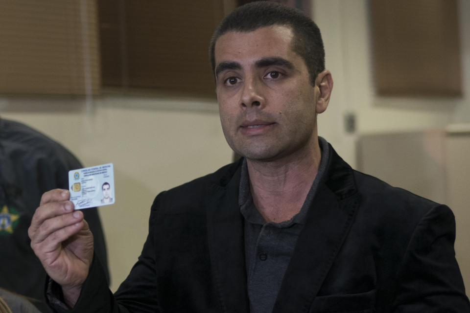 <em>The plastic surgeon shows his doctors licence as he speaks to the press (AP)</em>