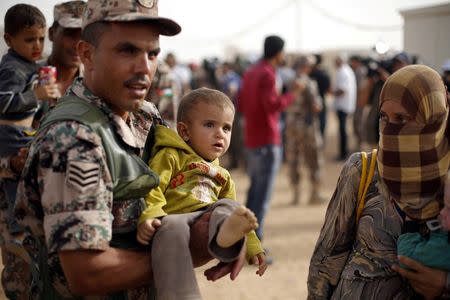 A Jordanian soldier carries a Syrian refugee child to help him board a Jordanian army vehicle with his family after they crossed into Jordanian territory, in Al Ruqban border area, near the northeastern Jordanian border with Syria, and Iraq, near the town of Ruwaished, 240 km (149 miles) east of Amman September 10, 2015. Picture taken September 10, 2015. REUTERS/Muhammad Hamed