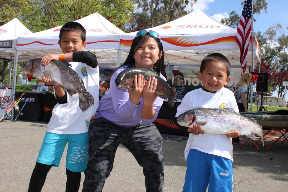 Seven year old Darren Alvarez, 9 year old Deslynn Le and 5 year old Evan Alvarez show off their big rainbows caught with Power Bait and Kastmasters at Rancho Seco Lake during the SMUD Trout Derby on April 6, 2024.