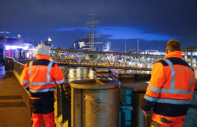 An den Piers stehen zwei Mitarbeiter der Firma Hamburg Wasser, die für die Schleusentore zuständig sind.  Für die deutsche Nordseeküste und Hamburg droht am Freitag ein schwerer Sturm.  Christian Charicius / Deutsche Presse-Agentur