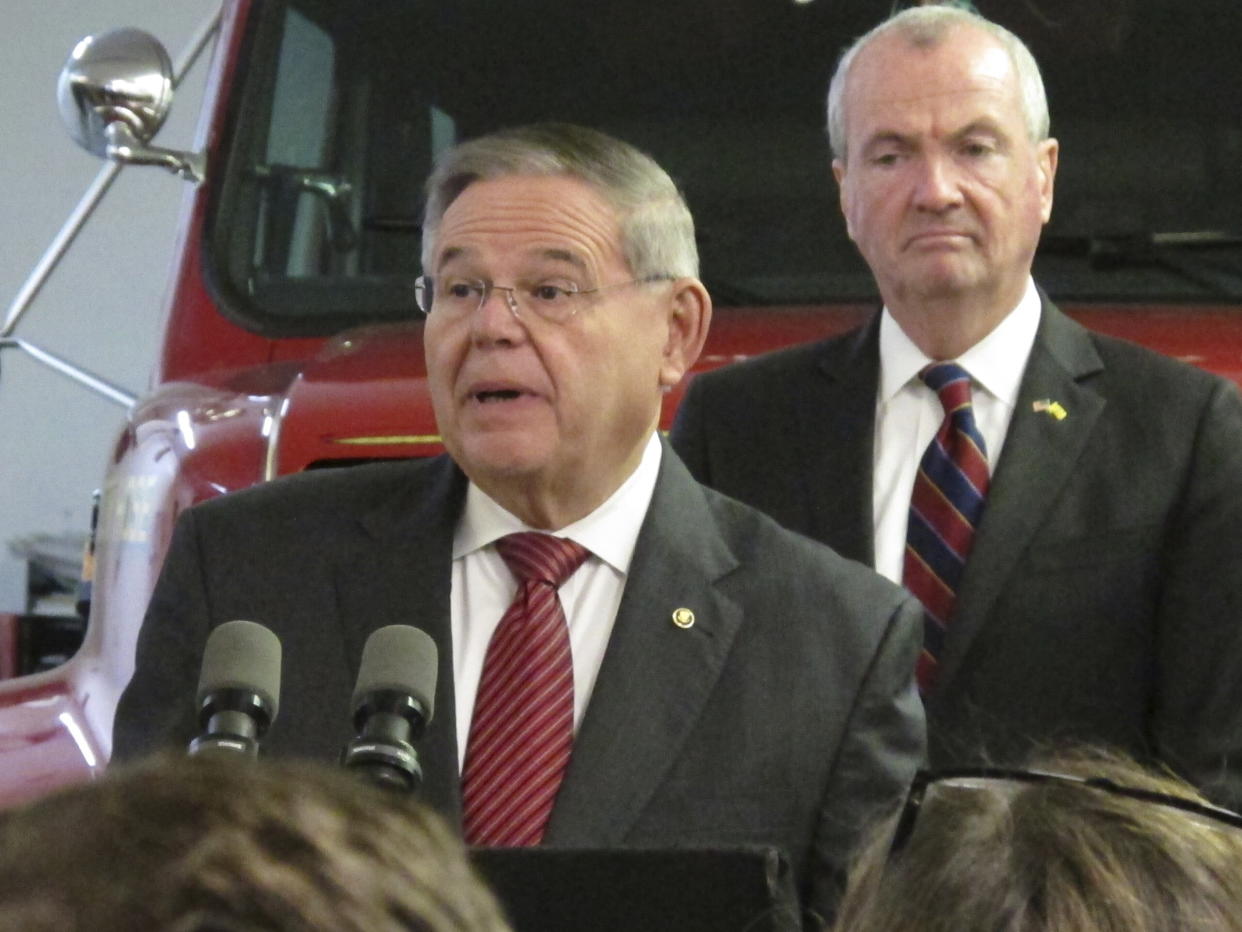 Senator Bob Menendez speaks at a podium as New Jersey Governor Phil Murphy listens behind him.