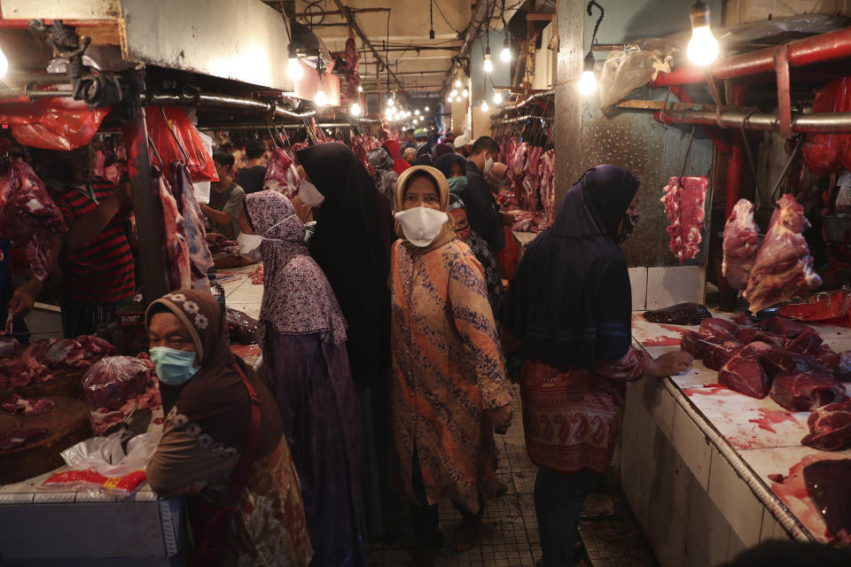 Muslim women shop for meat in preparation of the upcoming Eid al-Fitr holiday that marks the end of the holy fasting month of Ramadan amid fears of the new coronavirus outbreak at a market in Jakarta, Indonesia, Friday, May 22, 2020. (AP Photo/Achmad Ibrahim)