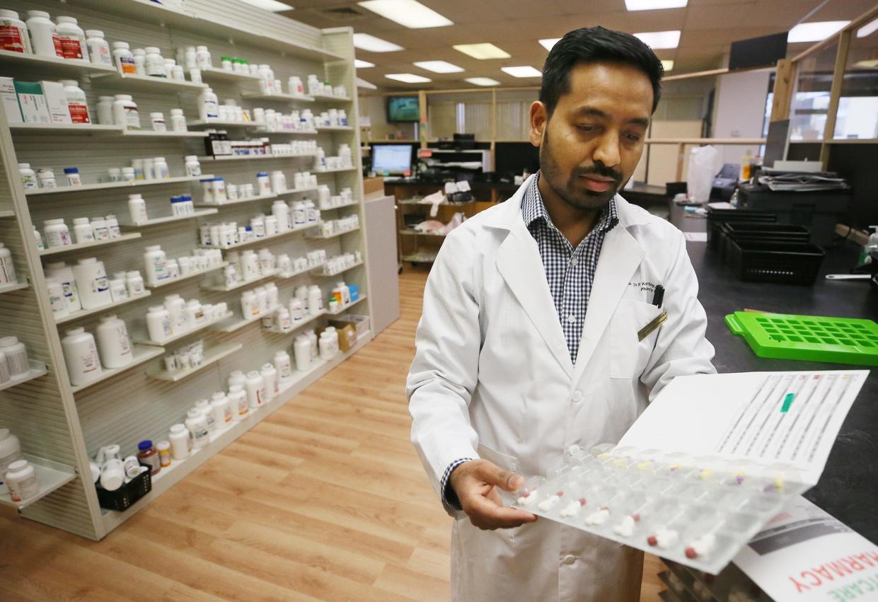 Ganga Kalikotay, pharmacist at BestCare Pharmacy in Akron, shows a prescription that is packaged in daily dosages in a bubble pack folder for patients who need assistance with taking their meds.