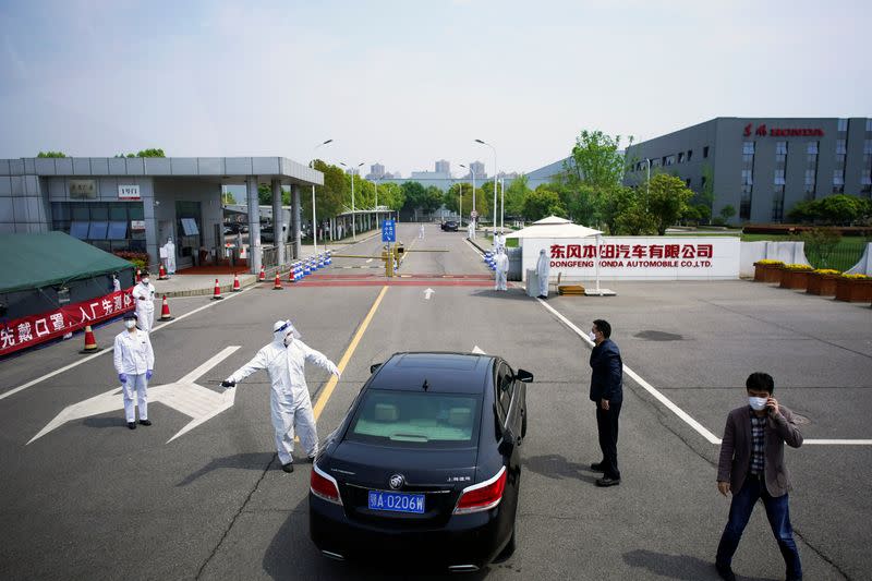 Workers in protective suits are seen at an entrance to a Dongfeng Honda factory in Wuhan