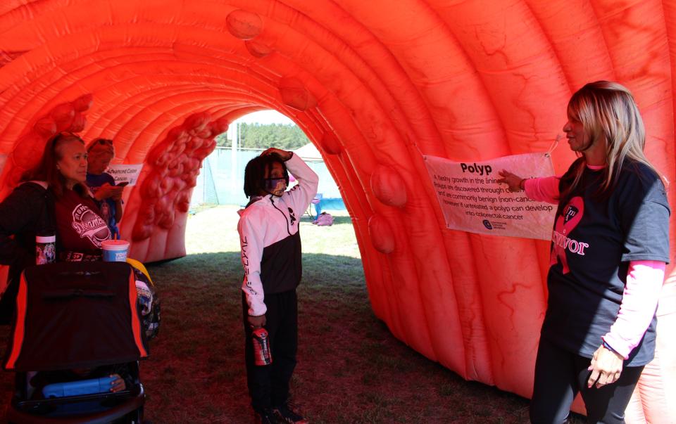 ​On the right, Sharon Rivera, Founder of the nonprofit organizations Saving Pennies 4 a Cure and Trials of Color, describes examples of irregularities that colorectal cancer screenings can detect inside a giant, inflatable colon at Donamatrix Day at Petersburg Sports Complex. Pictured from left to right, Daniel Lucas, volunteer Jennifer Katami, and Makoa Lucas.