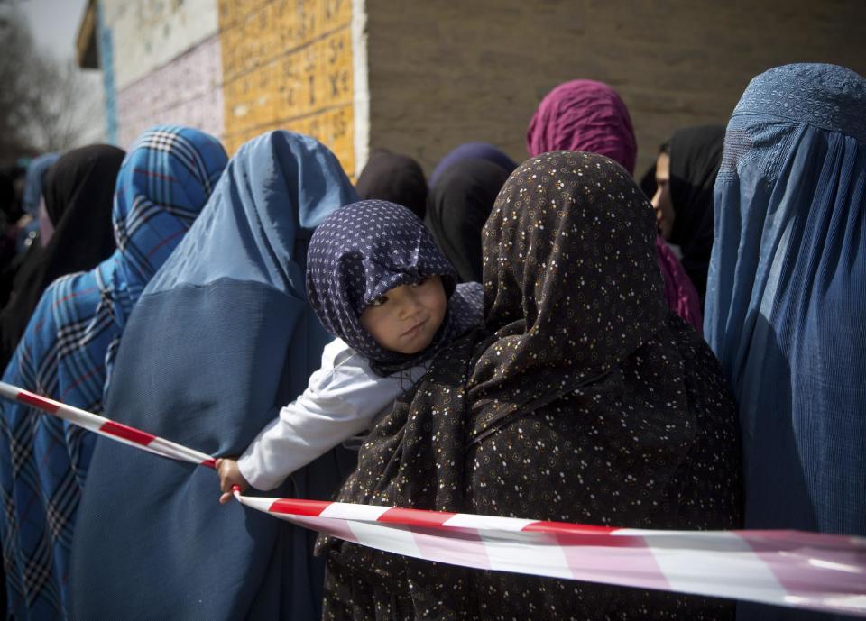 A child pulls a rope, which keeps Afghan women in line while waiting to get their registration card on the last day of voter registration for the upcoming presidential elections outside a school in Kabul, Afghanistan, Tuesday, April 1, 2014. Elections will take place on April 5. (AP Photo/Anja Niedringhaus)