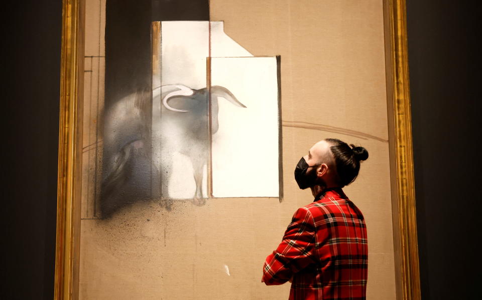 A staff member from the Royal Academy of Arts poses with “Study of a Bull”, 1991, by Francis Bacon in London, Britain, January 25, 2022.  REUTERS/Peter Cziborra