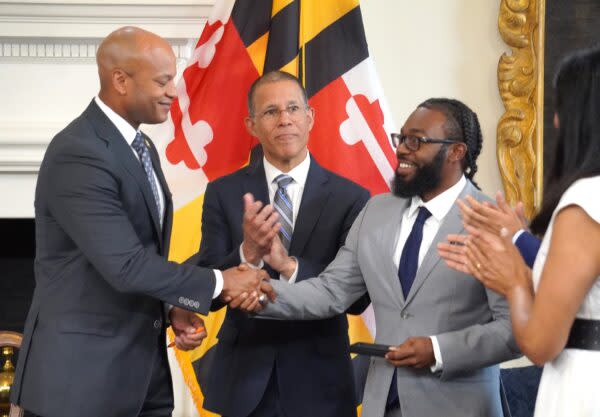  Gov. Wes Moore, left, gives a handshake to Shiloh Jordan on June 17 inside the governor’s reception room in Annapolis. Attorney General Anthony Brown looks on. Photo by William J. Ford.