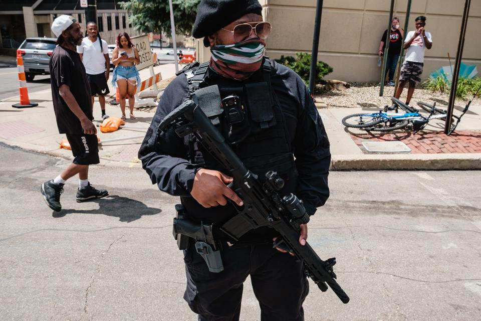An armed man with the group Nationwide Freedom Fighters watches the Akron NAACP-led march for Jayland Walker as it passes in front of the Harold K. Stubbs Justice Center on Sunday.