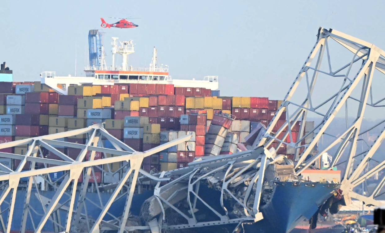 The steel frame of the Francis Scott Key Bridge sit on top of a container ship after the bridge collapsed in Baltimore, Md., on March 26, 2024. The bridge collapsed after being struck by a container ship, sending multiple vehicles and up to 20 people plunging into the harbor below. "Unfortunately, we understand that there were up to 20 individuals who may be in the Patapsco River right now as well as multiple vehicles," Kevin Cartwright of the Baltimore Fire Department told CNN. Ship monitoring website MarineTraffic showed a Singapore-flagged container ship called the Dali stopped under the bridge.