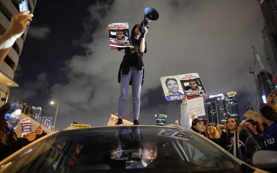 A woman holds a sign identifying Matan Zangauker (24) , one of the hostages taken captive by Palestinian militants in the Gaza Strip during the October 7 attacks, as she stands on the roof of a car during a demonstration by hostages' relatives and supporters in the Israeli coastal city of Tel Aviv on May 6, 2024, amid the ongoing conflict in the Gaza Strip between Israel and the Palestinian militant Hamas group.