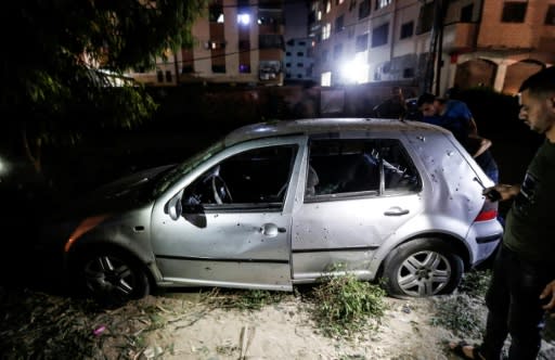 Palestinians look at a damaged car after a blast near a police checkpoint in Gaza City overnight