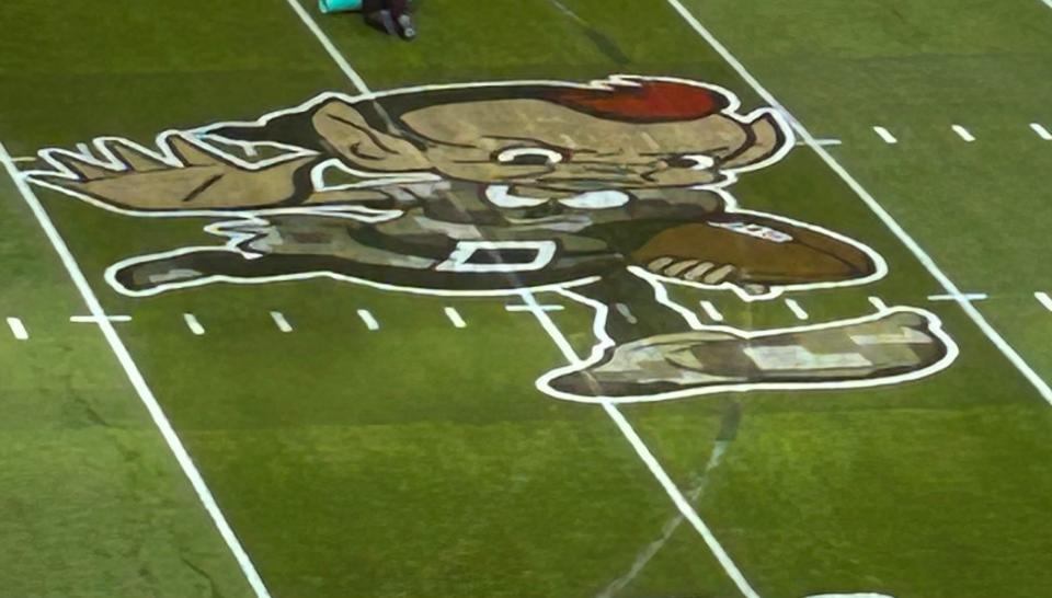 Brownie the Elf at midfield of the Browns stadium is painted in camo as part of the Salute to Service for their game against Tampa Bay on Sunday, Nov. 27, 2022, in Cleveland. Tire tracks from a vandalism incident early last week also pass through the logo.