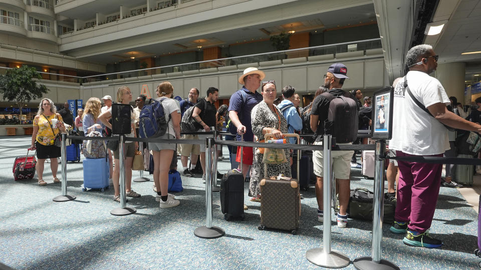 Pasajeros esperan en una fila para pasar por la zona de seguridad del Aeropuerto Internacional de Orlando, el miércoles 3 de julio de 2024, en Orlando, Florida. (AP Foto/John Raoux)