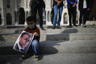 A child holds a photograph of France's President Emmanuel Macron, stamped with a shoe mark, during a protest against France in Istanbul, Sunday, Oct. 25, 2020. Turkish President Recep Tayyip Erdogan on Sunday challenged the United States to impose sanctions against his country while also launching a second attack on French President Emmanuel Macron. Speaking a day after he suggested Macron needed mental health treatment because of his attitude to Islam and Muslims, which prompted France to recall its ambassador to Ankara, Erdogan took aim at foreign critics. (AP Photo/Emrah Gurel)