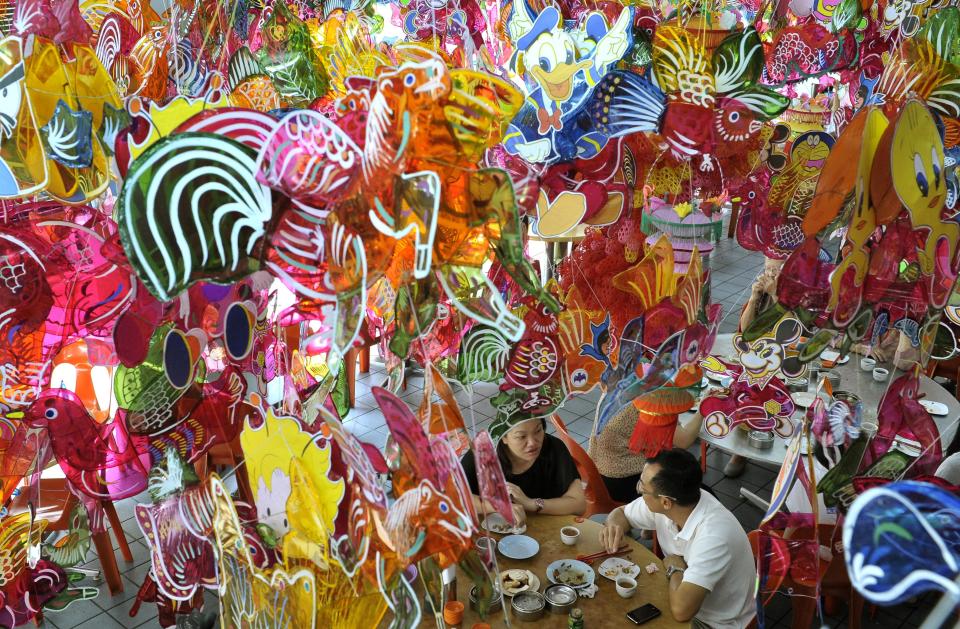 People eat under Chinese lanterns displayed at a restaurant as part of celebrations for the upcoming Mid-Autumn Festival on Penang Island, Malaysia, Tuesday, Sept. 25, 2012. (AP Photo/ Gary Chuan)