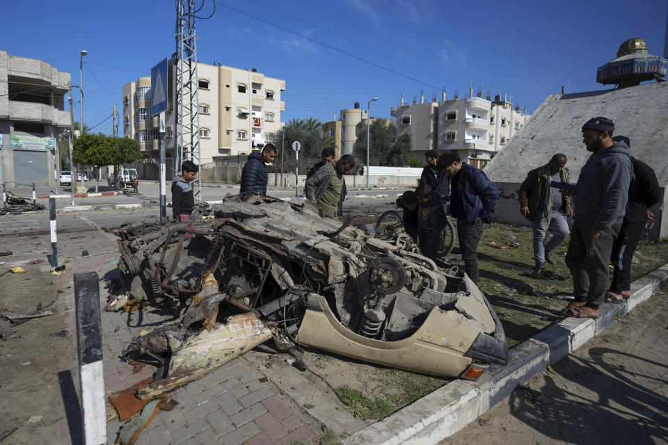 Palestinians inspect a vehicle wrecked by an Israeli airstrike in Deir al Balah, Gaza Strip, Wednesday, Feb. 21, 2024. (AP Photo/Adel Hana)