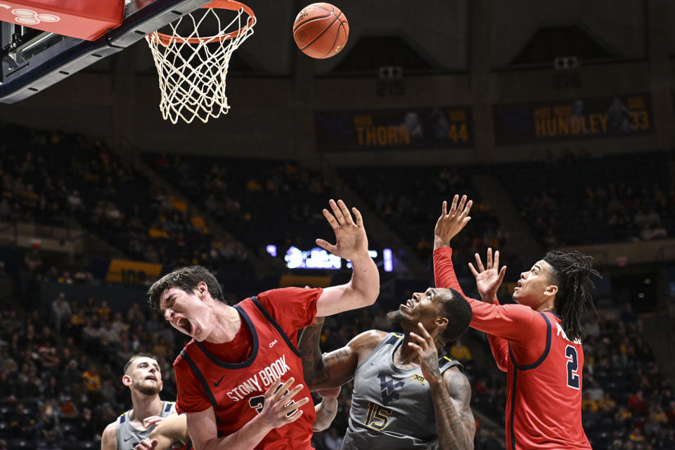 West Virginia forward Jimmy Bell Jr. (15) is fouled by Stony Brook center Keenan Fitzmorris (32) during the second half of an NCAA college basketball game Thursday, Dec. 22, 2022, in Morgantown, W.Va. (William Wotring/The Dominion-Post via AP)