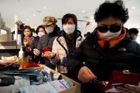 People wearing masks after the coronavirus outbreak wait in line to buy masks at a department store in Seoul