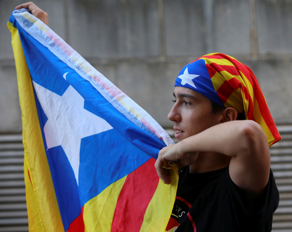 <p>A protestor holds up an Estelada (Catalan separatist flag) outside a Unipost office which was raided in search of material for the proposed October 1 referendum, in Terrassa, Spain, Sept. 19, 2017. (Photo: Albert Gea/Reuters) </p>