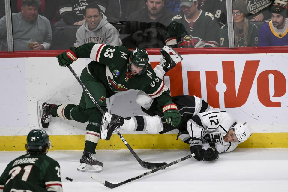 Minnesota Wild defenseman Alex Goligoski (33) checks Los Angeles Kings left wing Trevor Moore (12) into the boards during the first period of an NHL hockey game Tuesday, Feb. 21, 2023, in St. Paul, Minn. (AP Photo/Craig Lassig)