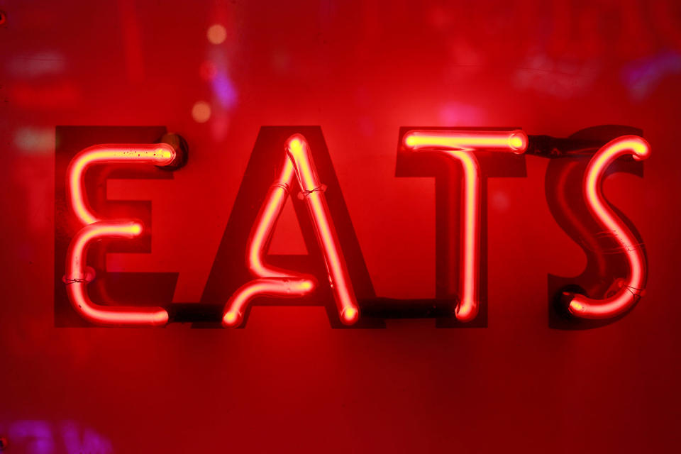 A neon light that reads ‘EATS’