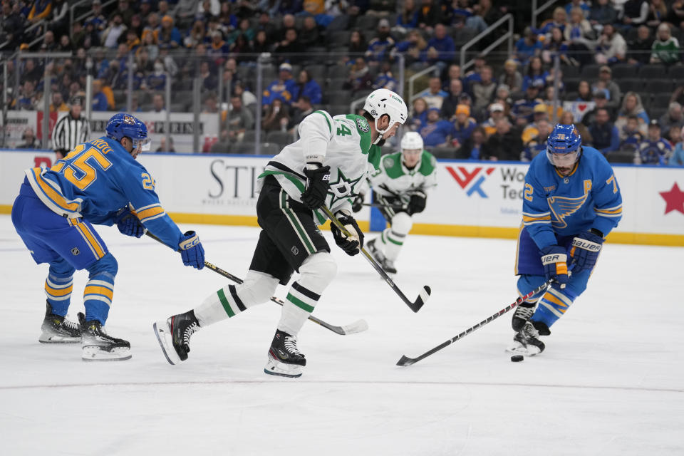 Dallas Stars' Jamie Benn, center, controls the puck between St. Louis Blues' Jordan Kyrou (25) and Justin Faulk (72) during the first period of an NHL hockey game Saturday, Dec. 16, 2023, in St. Louis. (AP Photo/Jeff Roberson)