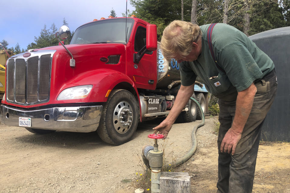 Brian Clark fills his water truck in Little River, Calif., on Wednesday, Aug. 4, 2021. Tourists flock to the picturesque coastal town of Mendocino for its Victorian homes and cliff trails, but visitors this summer will also find public portable toilets and dozens of signs on picket fences announcing the quaint Northern California hamlet: "Severe Drought Please conserve water." Clark has been selling water from his well outside of town and trucking it to the people who need it, but he said he can't keep up with the demand. (AP Photo/Haven Daley)