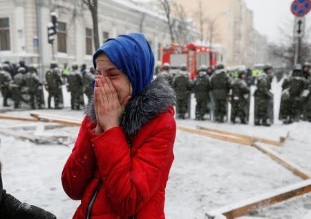 A woman cries as servicemen of the National Guard stand guard near a removed protest tent camp near the parliament building in Kiev, Ukraine March 3, 2018. REUTERS/Gleb Garanich