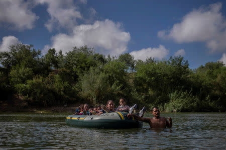 FILE PHOTO: A man proceeds with caution as he pulls a raft with families seeking asylum from Central America as they illegally cross the Rio Grande river into the United States from Mexico as seen from Granjeno, Texas October 5, 2018. REUTERS/Adrees Latif/File Photo