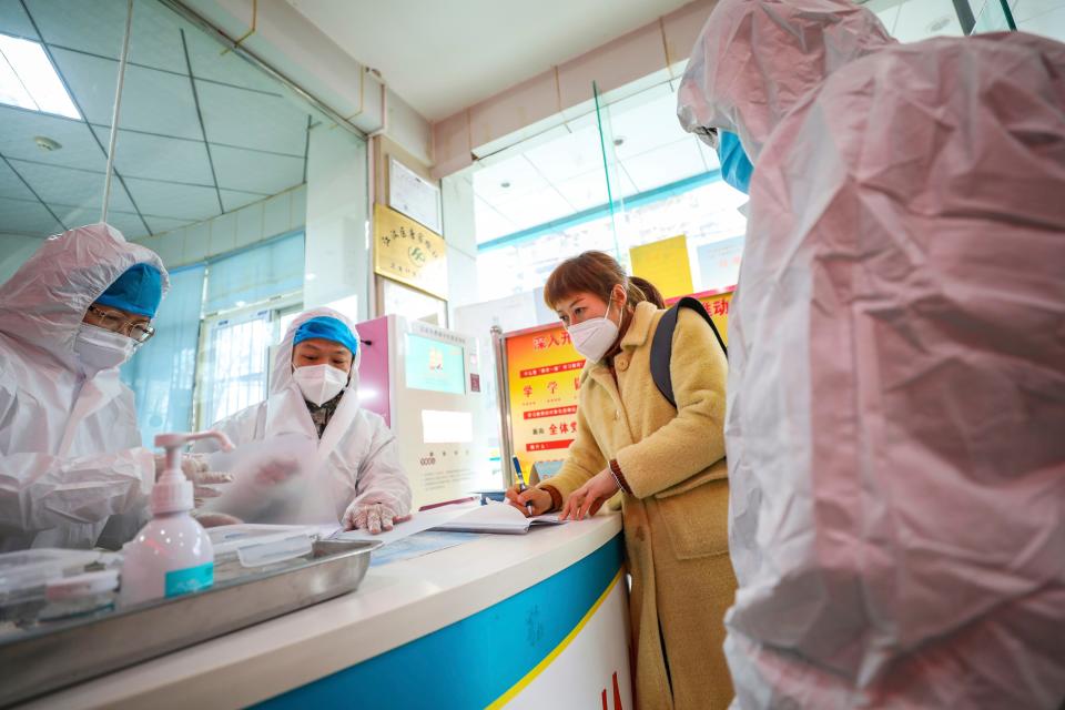 Medical workers in protective gear talk with a woman suspected of being ill with a coronavirus at a community health station in Wuhan in central China's Hubei Province, Monday, Jan. 27, 2020. China on Monday expanded sweeping efforts to contain a viral disease by extending the Lunar New Year holiday to keep the public at home and avoid spreading infection. (Chinatopix via AP)