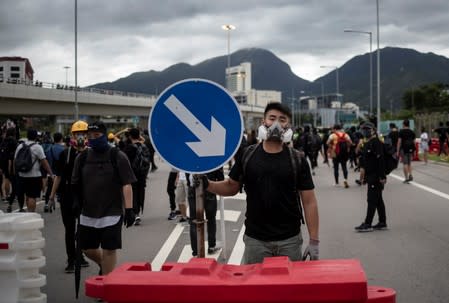 A protester holds a metal signage as he blocks the road with others at Hong Kong International Airport, in Hong Kong