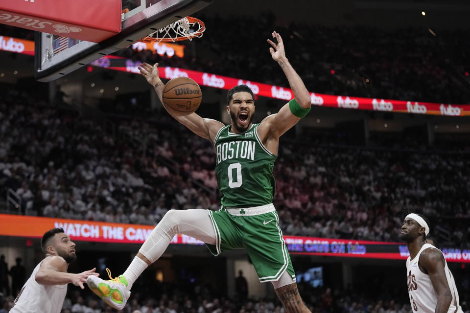 Boston Celtics forward Jayson Tatum (0) dunks between Cleveland Cavaliers guard Max Strus, left, and guard Caris LeVert during the second half of Game 3 of an NBA basketball second-round playoff series Saturday, May 11, 2024, in Cleveland. (AP Photo/Sue Ogrocki)