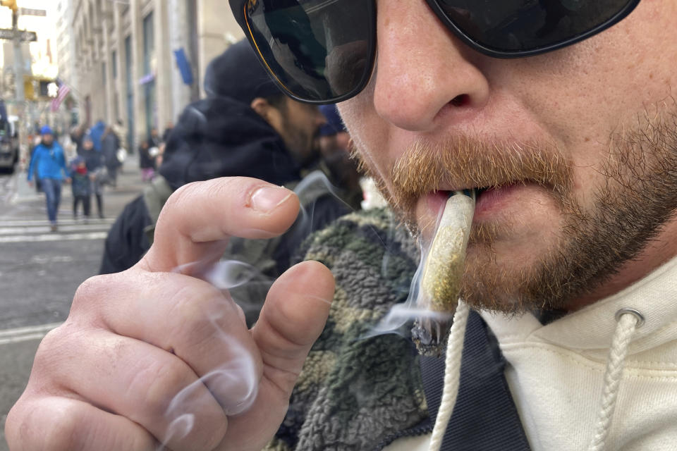 Ben Gilbert, 38, smokes marijuana in lower Manhattan outside the first legal dispensary for recreational marijuana in New York on Thursday, Dec. 29, 2022. New York is set to dramatically expand its legal weed market and issue more than 1,000 new licenses starting early next year, with a priority on retail. (AP Photo/Ted Shaffrey)