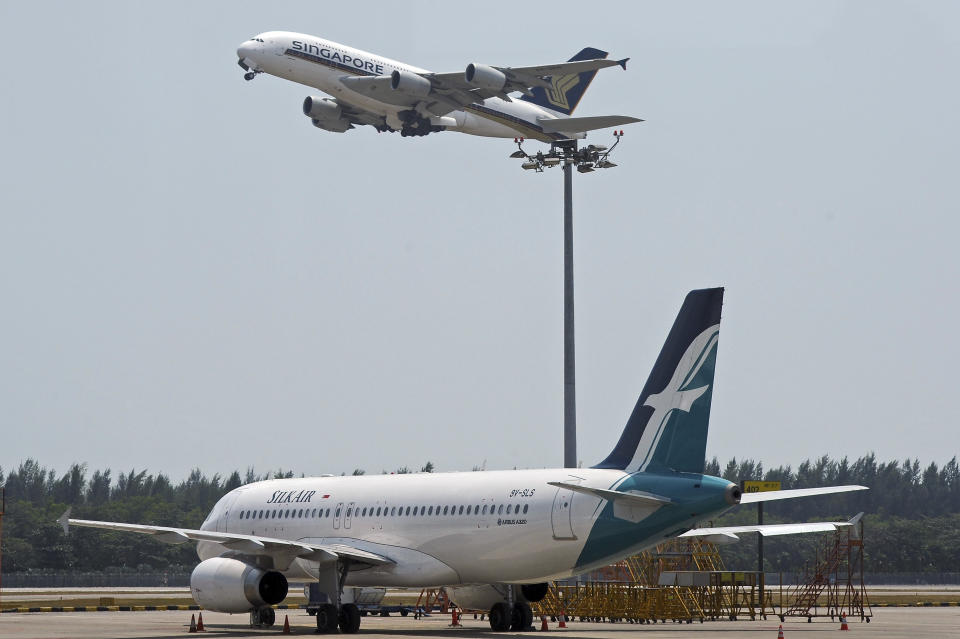 In this Feb. 10, 2014, photo, a Singapore Airlines Airbus A380, top, takes off at Singapore's Changi Airport as an Airbus A320 from its subsidiary airline, Silkair sits on the tarmac, bottom. Drones buzzing around Singapore's Changi Airport have caused the delay or diversion of 63 flights in the past week, triggering an official investigation and raising questions about the motives of the offenders. Regulators said Tuesday, June 25, 2019, that 18 flights at the airport were delayed and seven were diverted the night before "due to bad weather and unauthorized drone activities(AP Photo/Joseph Nair)